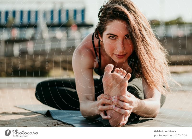 Zufriedene Frau macht Yoga in Kopf-zu-Knie-Pose Vorwärtsbeuge beweglich Dehnung Unterlage sich[Akk] entspannen Janu Sirsasana Asana positionieren Strand