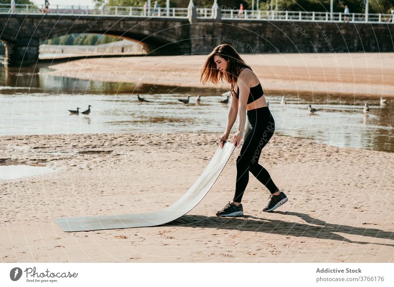 Frau bereitet Matte für Yoga-Übungen Unterlage vorbereiten Strand Sommer Fluss schlank friedlich Gesundheit passen Körper Sportbekleidung Wellness ruhig Sand