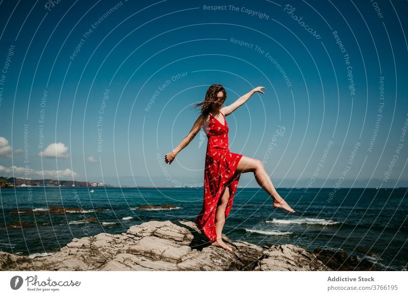 Anmutige Frau im Kleid auf felsigem Hügel rot Gleichgewicht Angebot Freude sich[Akk] bewegen schlank Barfuß Felsen Blauer Himmel wolkenlos Himmel (Jenseits)
