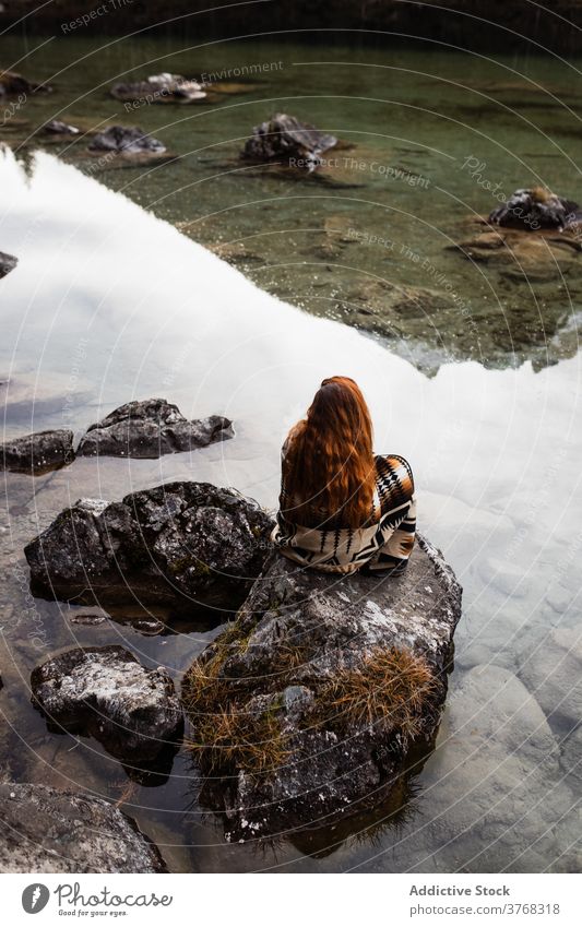 Frau sitzt auf Stein am Seeufer Ufer Herbst allein trist nachdenken stumm ruhig reisen Tourismus Deutschland Österreich Natur Wasser Windstille