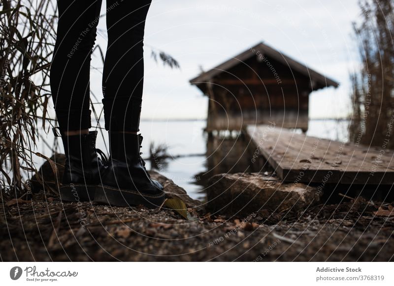 Anonymer Reisender steht in der Nähe von Pier am Seeufer im Herbst Tag Frau Baracke trist einsam Bein Ufer Natur Windstille ruhig reisen Tourismus Deutschland