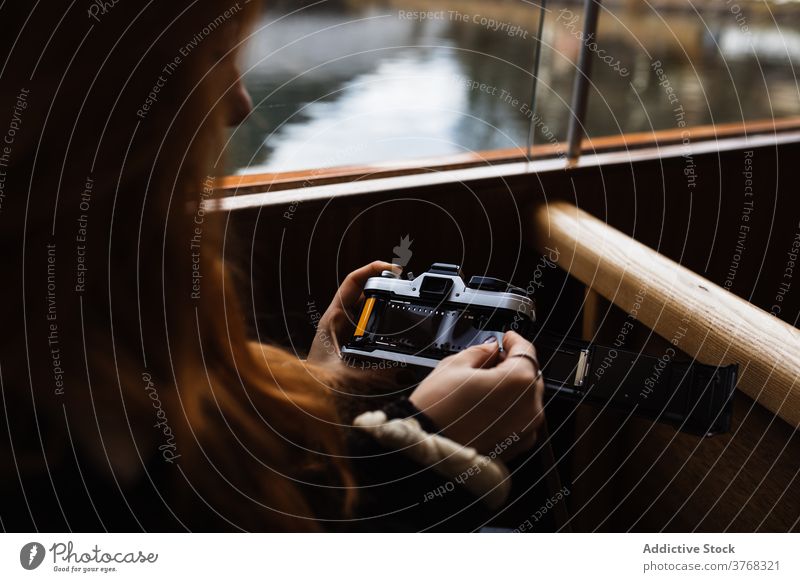 Frau wechselt den Film in einer Retro-Fotokamera, während sie in einem Boot fährt Fotoapparat retro Filmmaterial reisen Ausflug Fotograf Gefäße altmodisch