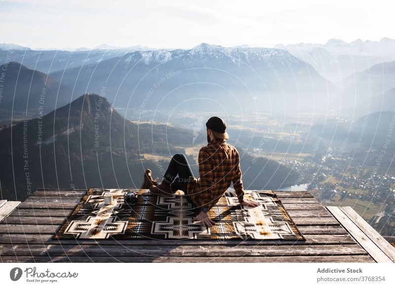 Reisender Mann sitzt auf einem Hügel und bewundert die Aussicht auf die Berge Aussichtspunkt Berge u. Gebirge Tourist Landschaft Kamm Morgen