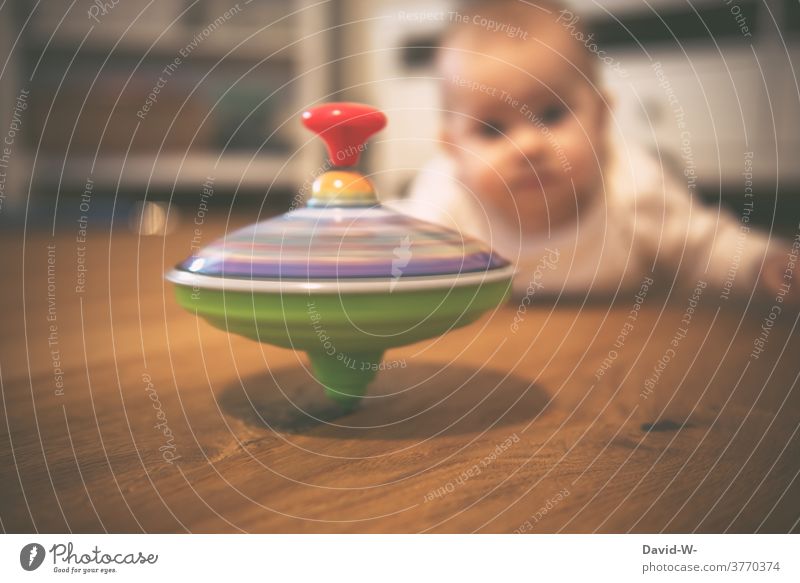 Baby beobachtet einen drehenden Kreisel Spielzeug Kleinkind beobachten neugierig Spielen Kindheit fasziniert beeindruckt