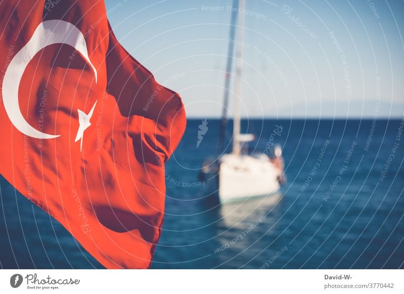 Eine türkische Fahne weht im Wind - ein Boot schwimmt im Hintergrund auf dem Meer Türkei Flagge Urlaub Ozean urlaubsziel Ferien & Urlaub & Reisen Segelboot