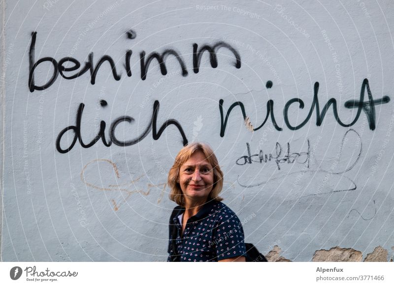 Motto der Woche: benimm dich nicht! Wand Frau Frauengesicht Mensch Erwachsene Farbfoto Mauer feminin Außenaufnahme Porträt Tag Blick in die Kamera Lächeln