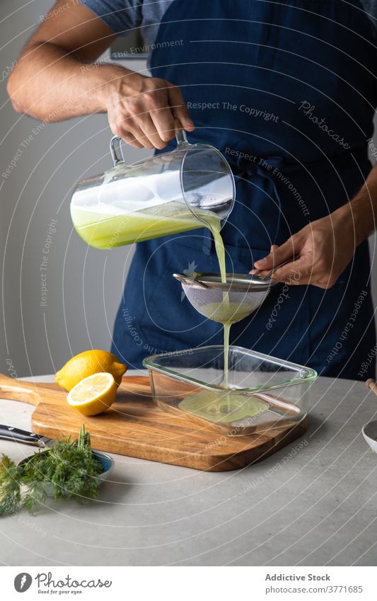 Kochen Filterndes grünes Getränk mit Sieb vorbereiten Saft natürlich Entzug Smoothie eingießen liquide Zitrone Lebensmittel frisch Küche organisch Vegetarier