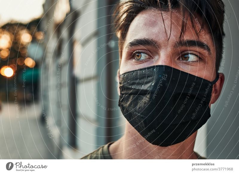 Junger Mann geht an einer Ladenfront im Stadtzentrum entlang und trägt die Gesichtsmaske, um eine Virusinfektion zu vermeiden Kaukasier Gespräch covid-19
