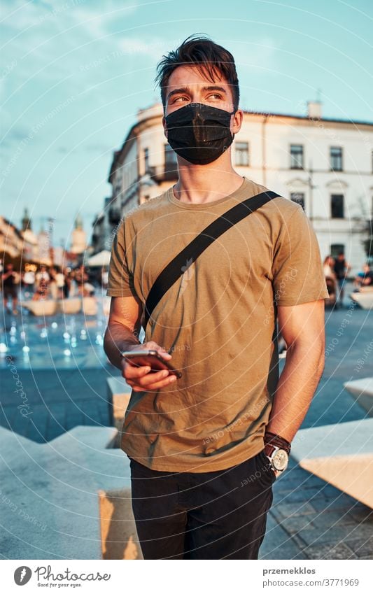 Junger Mann steht im Stadtzentrum und trägt die Gesichtsmaske, um eine Virusinfektion zu vermeiden Kaukasier Gespräch covid-19 Lifestyle Mundschutz Ausbruch