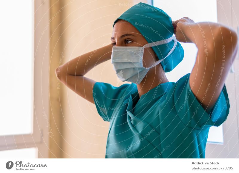 Weiblicher Sanitäter beim Anlegen der Maske im Krankenhaus angezogen Mundschutz Arzt Krankenpfleger Coronavirus Frau Bund 19 medizinisch Gesichtsmaske Uniform