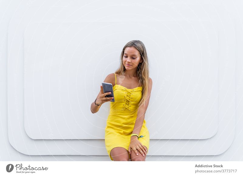 Charmante Frau mit Smartphone in der Stadt Großstadt schlendern Talkrunde soziale Netzwerke benutzend Surfen Sommer Kleid Gebäude Straße Browsen Mobile Telefon