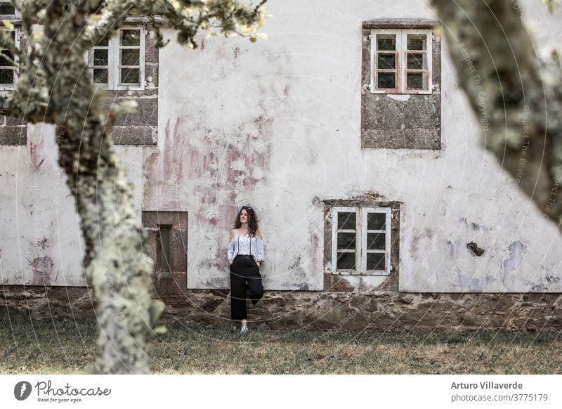 Frau, die sich an die Fassade eines alten Gebäudes mit der weißen Wand und einigen klassischen Fenstern lehnt Sommer Haus Mädchen Kaukasier ruhen Freiheit