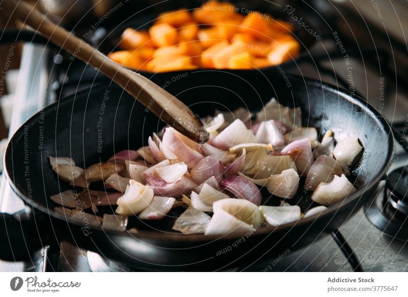 Anonyme Person brät Zwiebel in Pfanne braten vorbereiten Bestandteil rühren Koch Lebensmittel Rezept Küche Spachtel mischen kulinarisch selbstgemacht Gemüse
