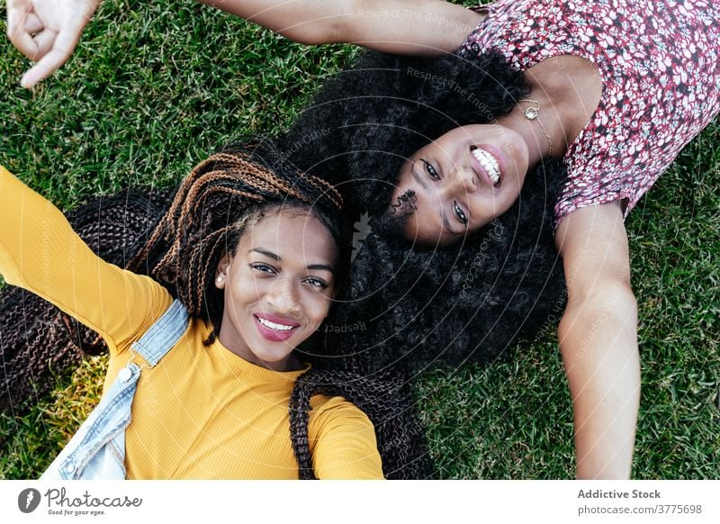 Glückliche schwarze Frauen liegen auf grünem Gras Freund Zusammensein Lügen heiter Sommer genießen Freundschaft Freundin jung Afroamerikaner ethnisch Afro-Look