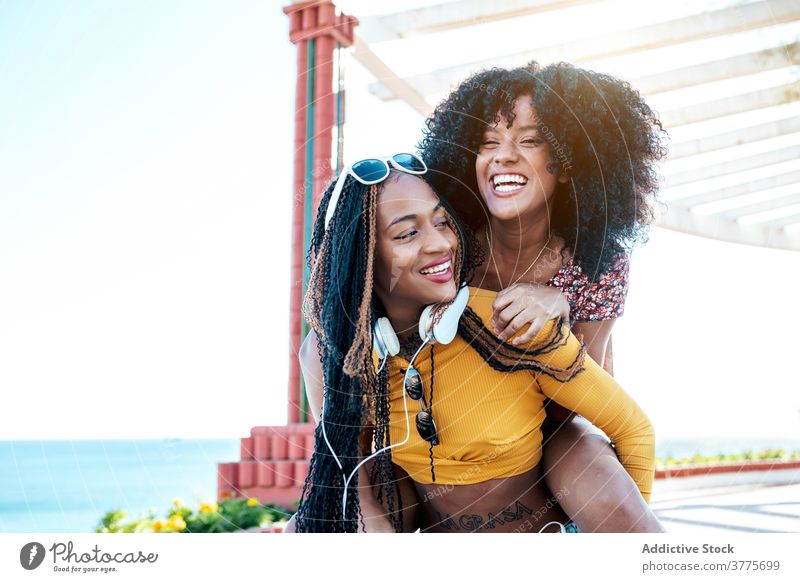 Schwarze weibliche Freunde haben Spaß auf Böschung im Sommer Huckepack Spaß haben Frauen Freude Wochenende bester Freund Spazierweg ethnisch schwarz