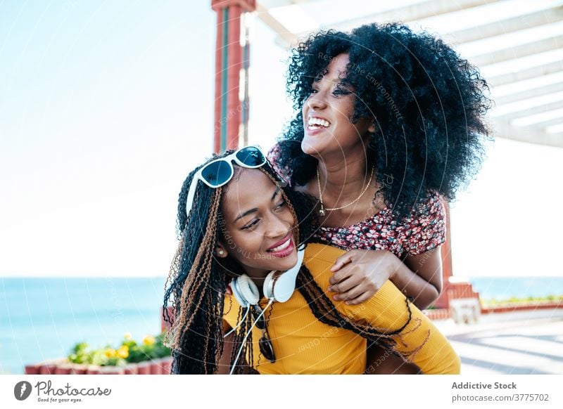 Schwarze weibliche Freunde haben Spaß auf Böschung im Sommer Huckepack Spaß haben Frauen Freude Wochenende bester Freund Spazierweg ethnisch schwarz