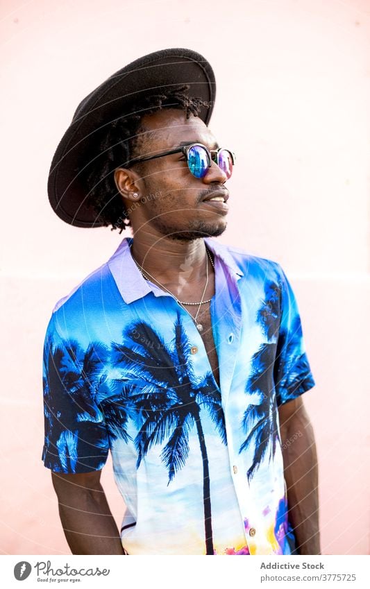 Stilvolle schwarze Mann in Hut und Sonnenbrille in der Stadt Hemd Handfläche Baum drucken trendy selbstbewusst Bestimmen Sie gutaussehend männlich ethnisch