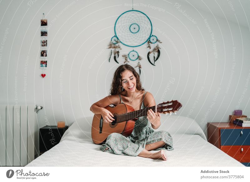 Positive Frau spielt Gitarre im Schlafzimmer Gitarrenspieler Musik spielen heiter Lachen Talent unterhalten sorgenfrei Instrument ethnisch akustisch gemütlich