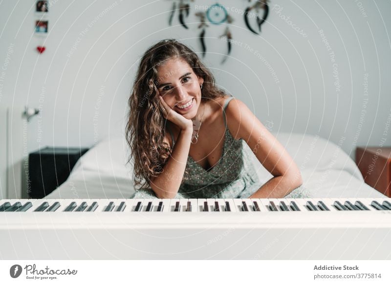 Frau mit modernem Synthesizer zu Hause elektrisch Klavier Musiker heimwärts sich[Akk] entspannen Klang Bett ethnisch Melodie ruhen gemütlich sitzen Gesang