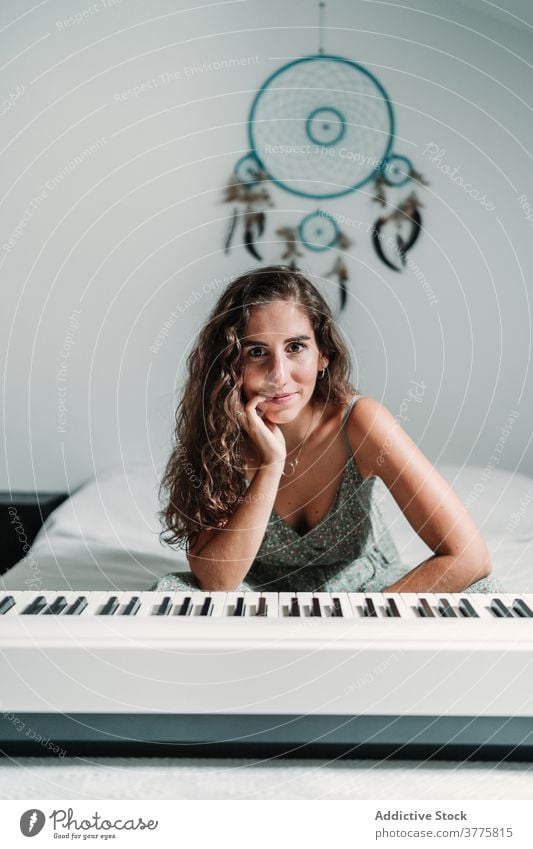 Frau mit modernem Synthesizer zu Hause elektrisch Klavier Musiker heimwärts sich[Akk] entspannen Klang Bett ethnisch Melodie ruhen gemütlich sitzen Gesang