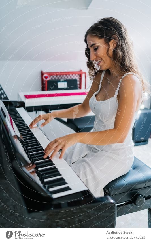 Lächelnde Frau spielt Klavier im Wohnzimmer spielen Musik Musiker Probe Talent Fähigkeit kreativ Melodie ethnisch modern Appartement Gesang ausführen Klang