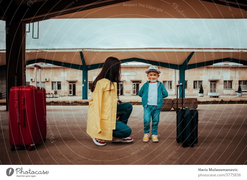 Mutter und Kind reisen mit Gesichtsmaske auf dem Bahnhof Erwachsener Tasche Gepäck Taschen schön Kaukasier Großstadt Corona-Virus Covid-Reisen covid-19