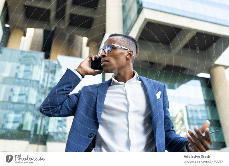 Seriöser Geschäftsmann spricht mit Smartphone in der Innenstadt Unternehmer Büro Gebäude sprechen diskutieren Anzug Bestimmen Sie benutzend reden männlich