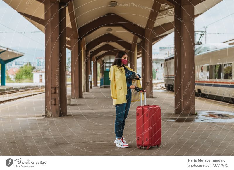 Frau mit Maske und Reisetasche wartet am öffentlichen Bahnhof Erwachsener attraktiv Tasche Gepäck schön Business Kaukasier Großstadt Coronavirus covid-19