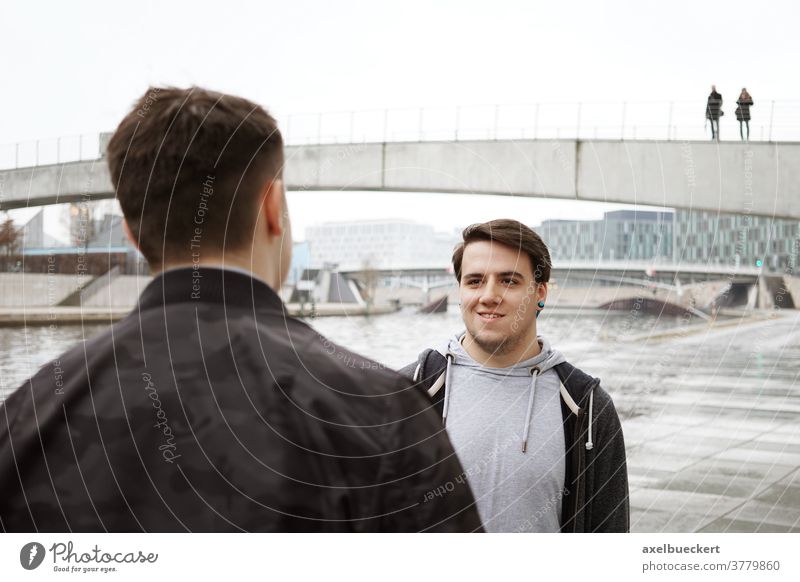 zwei männliche Freunde im Teenageralter unterhalten sich am Fluss Menschen echte Menschen Gespräch sprechend Lifestyle offen authentisch wirklich Mann Männer