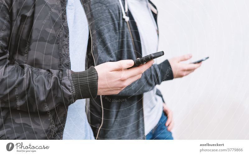 zwei männliche Teenager, die ein Smartphone benutzen Handy süchtig unsozial Telefon jung Männer Freunde benutzend Technik & Technologie Medien Netzwerk digital
