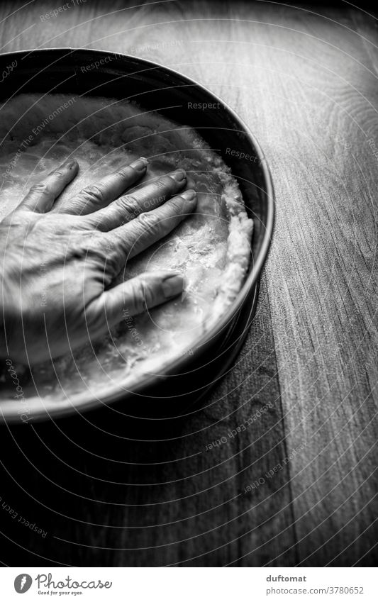Schwarz-Weiß Bild einer Hand die Kuchenteig in eine Springform knetet. Teig backen Schwarzweißfoto Torte Patisserie Backwaren rustikal kneten Vogelperspektive