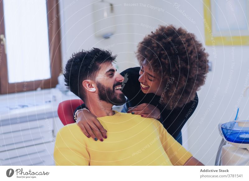Fröhliche schwarze Frau unterstützt Freund in Zahnarztpraxis Paar Büro abstützen heiter tröstlich besuchen Zusammensein Klinik die sich gegenseitig ansehen jung