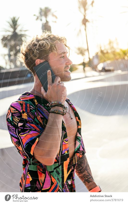 Fröhlicher Hipster, der im Skatepark mit seinem Smartphone spricht Skater Mann reden Stil trendy Kommunizieren Anruf Aktivität Rampe jung männlich Schlittschuh