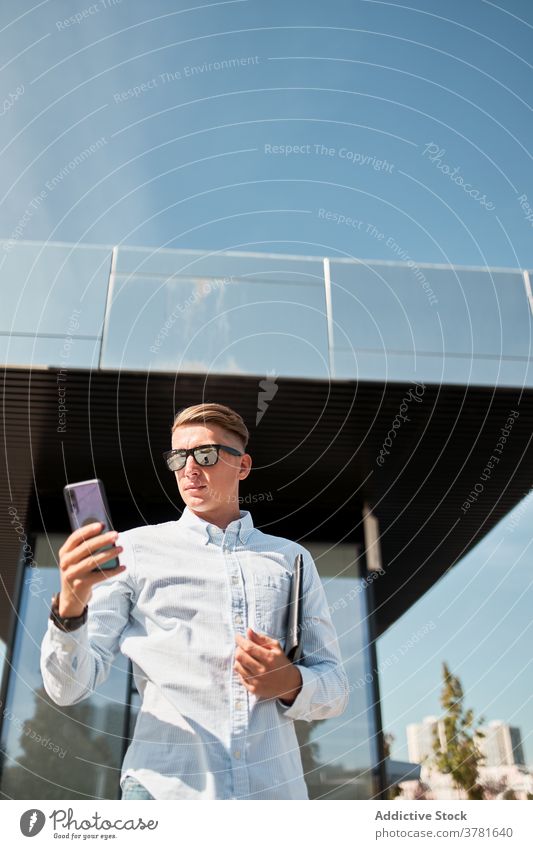 Moderner Mann mit stilvoller Sonnenbrille am Telefon in der Stadt Stil Smartphone urban modern selbstbewusst trendy jung männlich Mobile Kommunizieren Anschluss