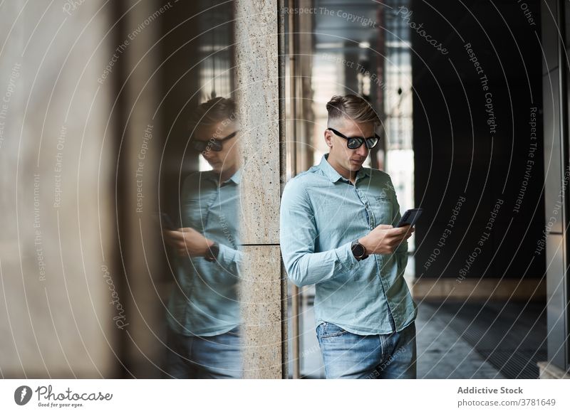 Seriöser Mann benutzt Smartphone in der Stadt Stil Großstadt Browsen gutaussehend trendy maskulin benutzend Talkrunde männlich Bekleidung Kleidung urban