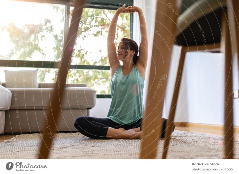 Serene Frau macht Yoga auf dem Boden zu Hause üben heimwärts beweglich Lotus-Pose Beine gekreuzt padmasana Dehnung friedlich Sportbekleidung Wellness Asana