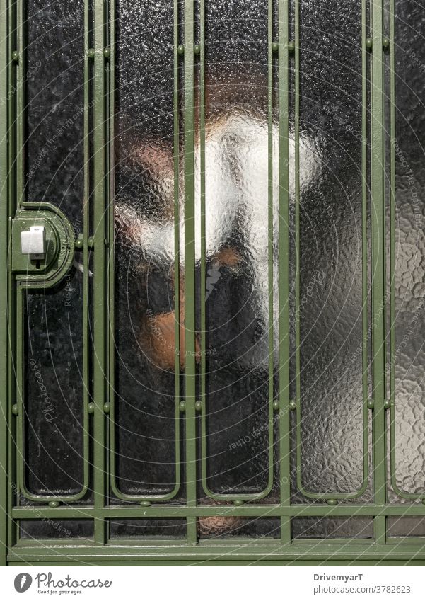 Silhouette einer Frau mit weißer Jacke in einer Eingangshalle von außen durch eine Metallglastür gesehen Tür Glas jemand anonym Person undurchsichtig