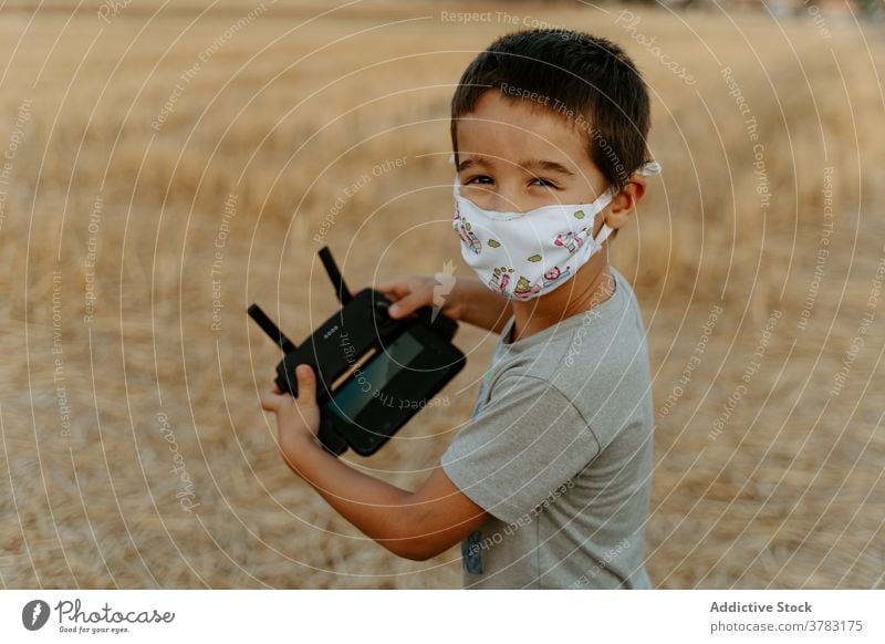 Kleines Kind betreibt Drohne im Feld Dröhnen Kontrolle abgelegen arbeiten benutzend Mundschutz Junge spielen wenig asiatisch ethnisch männlich Kindheit Spiel