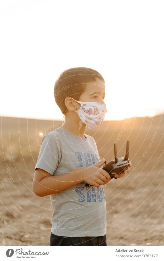 Kleines Kind betreibt Drohne im Feld Dröhnen Kontrolle abgelegen arbeiten benutzend Mundschutz Junge spielen wenig asiatisch ethnisch männlich Kindheit Spiel