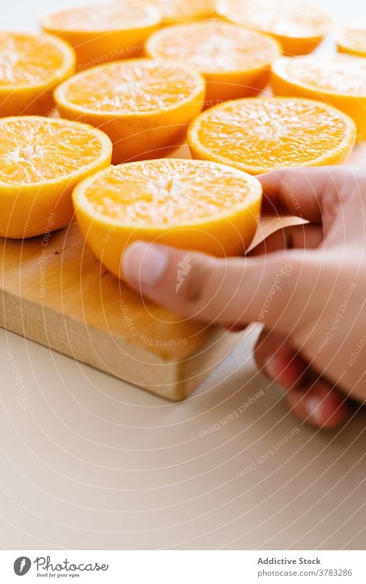 Crop-Person mit Orangen auf Schneidebrett Hälfte orange Ordnung Linie Orden Reihe Atelier Frucht hölzern reif Vegetarier Lebensmittel frisch Ernährung Diät