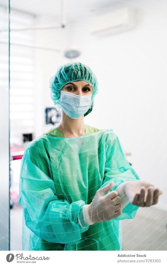 Weiblicher Arzt in der Tierklinik schaut in die Kamera Tierarzt Veterinär Operationssaal Frau vorbereiten angezogen Handschuh Uniform Klinik Mundschutz Chirurg