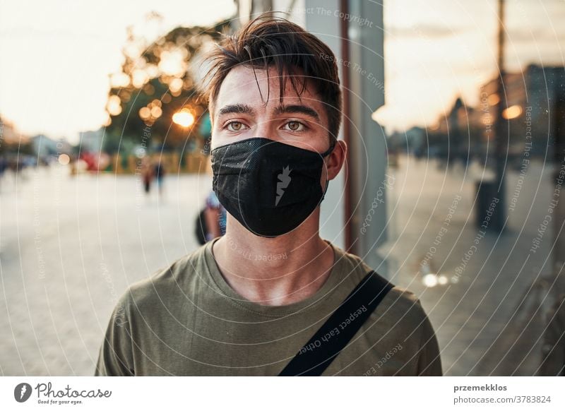 Junger Mann geht an einer Ladenfront im Stadtzentrum entlang und trägt die Gesichtsmaske, um eine Virusinfektion zu vermeiden Kaukasier Gespräch covid-19