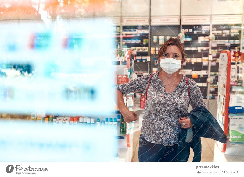 Frau kauft in der Apotheke ein, kauft Medikamente, trägt Gesichtsmaske während des Ausbruchs des pandemischen Coronavirus Chemiker Werkstatt Mundschutz covid-19