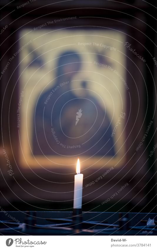 Eine brennende Kerze in der Kirche mit Maria im Hintergrund brennt leuchten kirche glaube Religion Hoffnung Gebet Trauer Weihnachten Corona