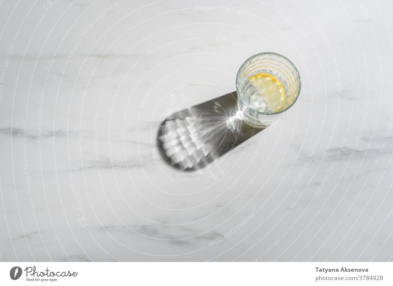 Wasserglas mit Zitronenstücken auf Marmorgrund. Immunitätsförderndes Morgengetränk trinken frisch Frucht Glas kalt Zitrusfrüchte Getränk
