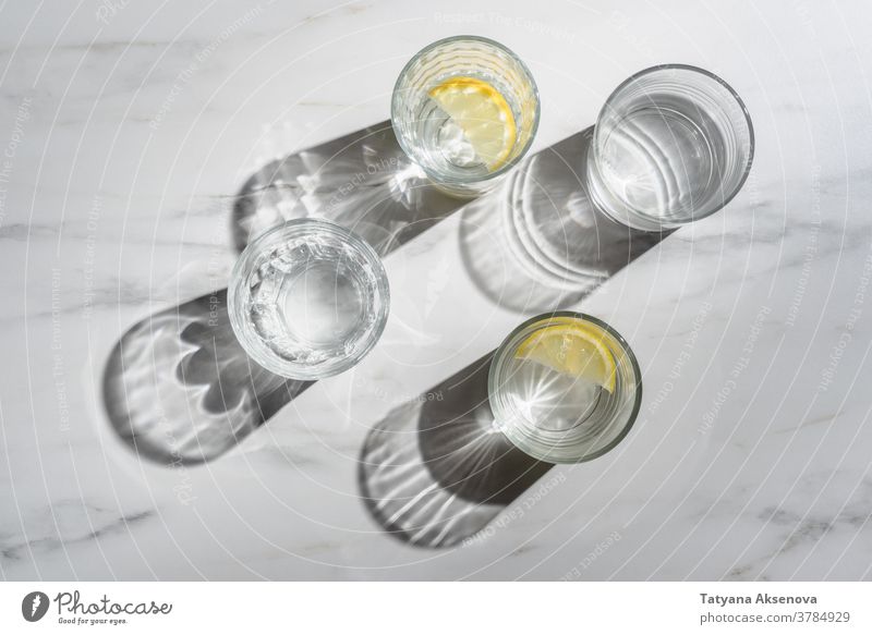 Wasserglas mit Zitronenstücken auf Marmorgrund. Immunitätsförderndes Morgengetränk trinken frisch Frucht Glas kalt Zitrusfrüchte Getränk