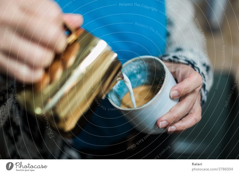 Frau in Blau gießt mit Milchschaum Latte Art in ein Glas Milchkaffee in der Hand mit kupferkanne gießen milchschaum Barista café au lait Espresso