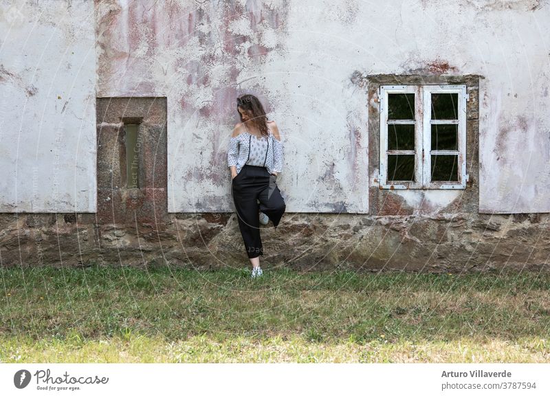 Frau lehnt an der Fassade eines alten Hauses mit weißer Wand und einigen klassischen Fenstern Sommer Mädchen Kaukasier ruhen Freiheit Herbst hölzern Porträt