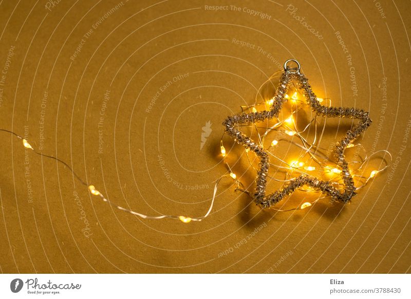 Weihnachtsstern mit leuchtender Lichterkette auf gelbem Hintergrund. Weihnachten. Stern Advent Weihnachtsdekoration Copyspace weihnachtlich