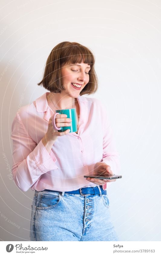 Frau, die Kaffee trinkt und ein Smartphone benutzt benutzend Gerät soziale Netzwerke Texten Handy Lächeln Tasse rosa modern jung trinken positiv Optimist